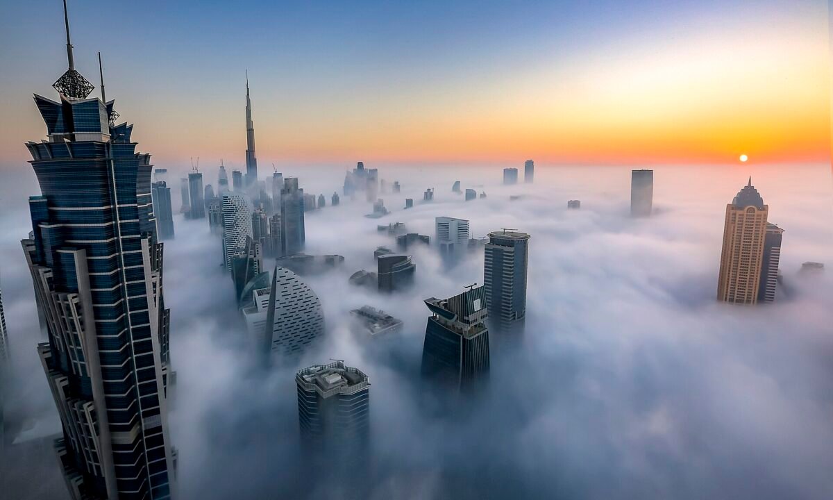 Dubai free zone office towers rising above morning fog at sunrise